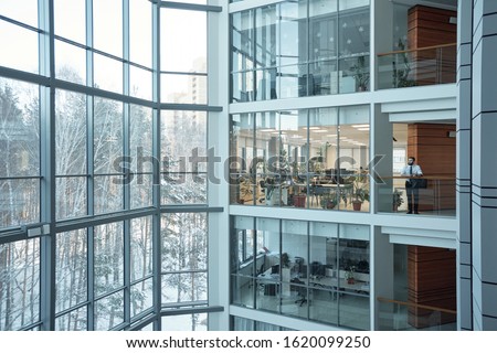 Interior of contemporary multi-floor business center with large windows and many offices in front of them Royalty-Free Stock Photo #1620099250