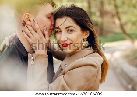 Cute couple in a park. Lady in a brown jacket.