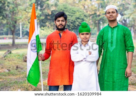 Three kids and boy of different age and different religion hearing tricolor dress and holding Indian National flag. Indian kids celebrating Republic or Independence day of India. 