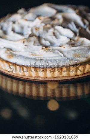 Tasty lemon meringue pie. Traditional french sweet pastry tart. Delicious, appetizing, homemade dessert with lemon cream. Copy space, closeup. Selective focus. Black background. Toned
