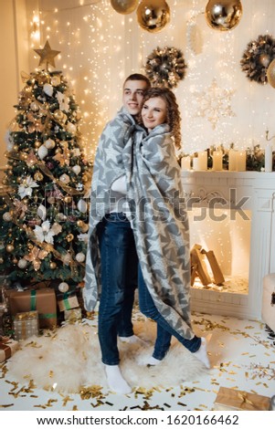  Studio portrait photo. Valentine's day. Loving couple. Happy couple in love, posing. Valentines day. Christmas. Cute couple wrapped in gray plaid with white stars celebrating New Year.