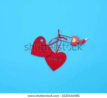 red felt hearts hanging on an iron lock, blue background. Holiday celebration concept. 