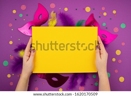 Festive, colorful mardi gras or carnivale mask and accessories over purple background. Party invitation, greeting card, venetian carnivale celebration concept. Flat lay, top view, copy space