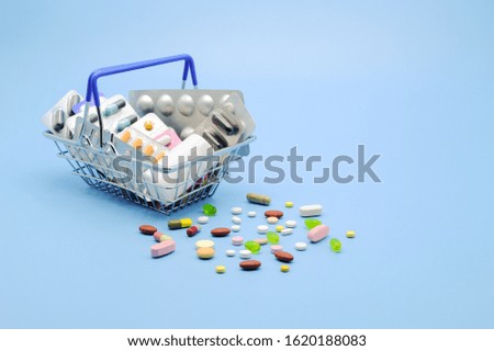 Buy and shopping medicine concept. Various capsules, tablets and medicine in shop basket on a blue background. Creative idea for health care, health insurance and pharmaceutical company. Copy space.