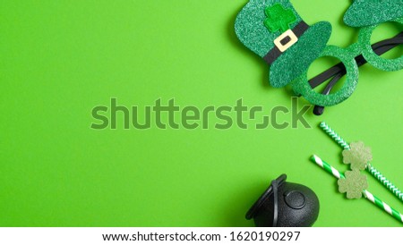 Happy St Patrick's day concept. Top view Patricks Day glasses, pot of gold, drinking straws on green background. St Patrick’s day party invitation card template, banner design