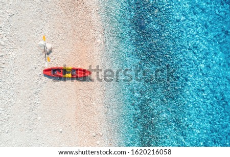 Aerial view of empty sandy beach with red canoe, sea coast with transparent blue water in sunny bright day in summer. Travel in Croatia. Top view of boats. Landscape with kayaks at sunset. Travel