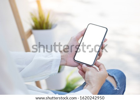 Mockup image blank white screen cell phone.woman hand holding texting using mobile sitting at coffee shop.background empty space for advertise text.people contact marketing business,technology 