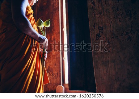 A Buddhist monk holding a lotus flower used for rituals of Buddhism.