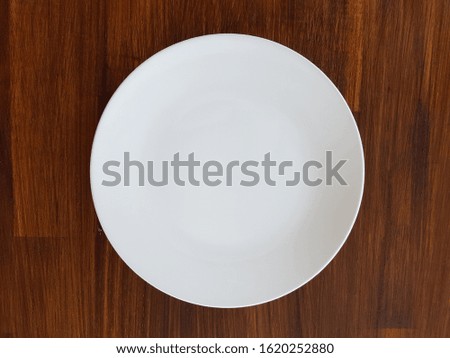 Empty white plate on the wooden table top view, copy space.