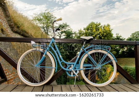 Image of retro looking brand new blue bicycle leaned on wooden bridge 
