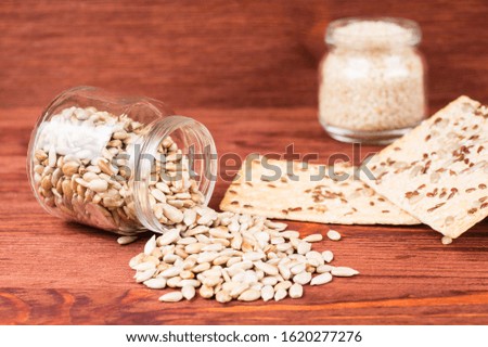 sunflower seeds in a jar with  crispy wheat cakes on a red wooden background. vegetarian food, eco food concepts