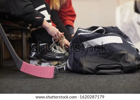 Close up of unrecognizable young woman tying shoelaces on skates while preparing for hockey practice in locker room, copy space Royalty-Free Stock Photo #1620287179