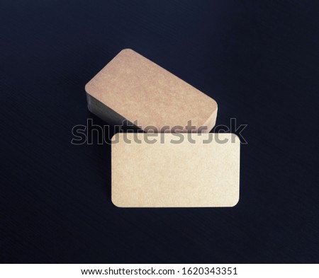 Brown paper business cards on black wooden background. Mockup for branding identity.