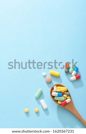 Large amount of drugs and wooden spoon full of drugs on the blue background -- the concept of medical health
