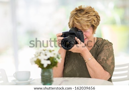 pretty senior woman photographing flowers on the table