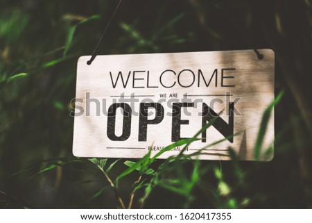 Wooden open sign hanging on bamboo tree with green nature bokeh sunlight background. Business finance and service concept. Vintage tone filter effect color style.
