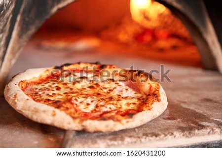 Baked tasty margherita pizza in Traditional wood oven in Naples restaurant, Italy. Original neapolitan pizza. Red hot coal. Royalty-Free Stock Photo #1620431200