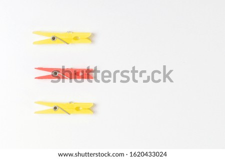concept with clothespins on a white background, two yellow and one red clothespin