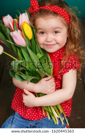 Cute little girl holding tulip bouquet. Studio portrait. Girl with tulips. Mother's Day, March 8, International Women's Day. 