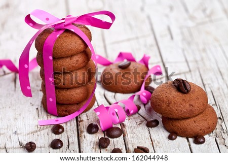 chocolate cookies tied with pink ribbon and coffee beans on rustic wooden background