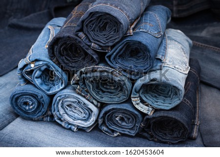Rolled jeanses of different shades on denim background. Close-up