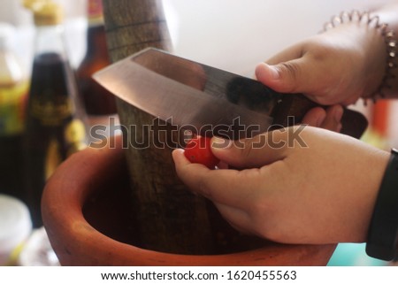 Picture of a hand holding a knife to cut tomatoes