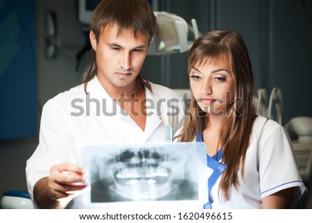 Young couple man and woman in dental clinic, looking at dental picture. Dental health and medical care concept
