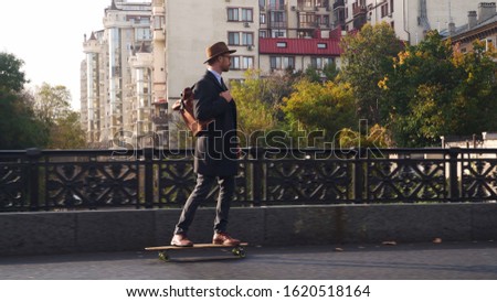 Hipster businessman skateboarding at the bridge at sunny day