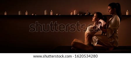 Young fit woman has Thai massage at luxury spa. Warm inviting colors, calm atmosphere, charming light. Copy space Royalty-Free Stock Photo #1620534280