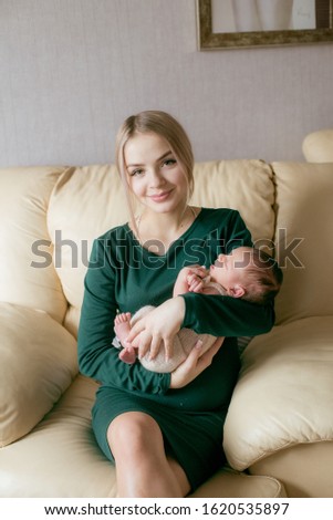 Young beautiful blond hair mamaso with a baby in her arms at home. Happy motherhood