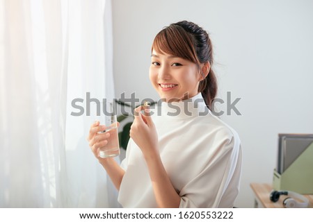 Young Asian woman drinking medicine with water glass. Royalty-Free Stock Photo #1620553222