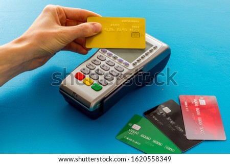 Contactless payment, paypass. Hand hold bank card near terminal on blue background