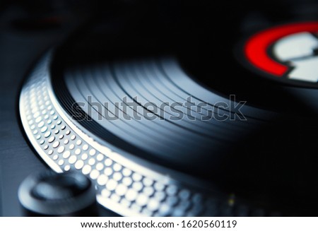 Vinyl record disc on retro turntable player device. Professional dj turn table in closeup. Analog audio equipment for disc jockey. Curated collection of royalty free music images and photos for poster