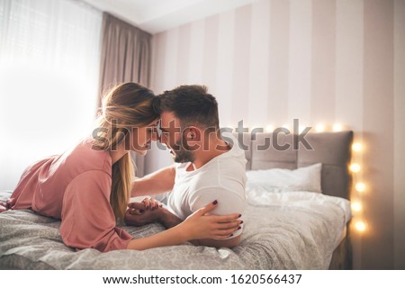 A man and a woman lie on the bed and exchange tenderness while holding hands. Royalty-Free Stock Photo #1620566437