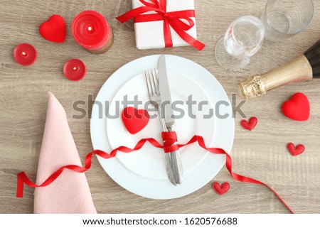 Festive table setting for Valentine's Day with cutlery, gift boxes and hearts on the table. Space for text. View from above.
