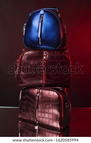 Three leather bags of different colors on a beautiful studio background