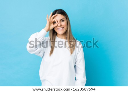 Young caucasian woman isolated excited keeping ok gesture on eye.