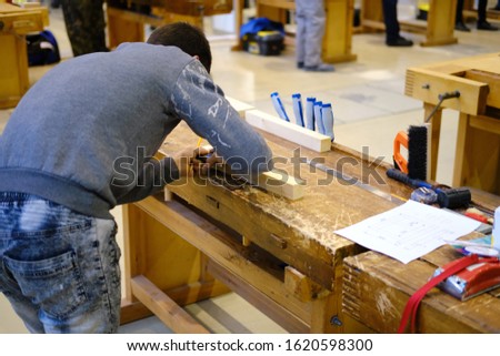 Carpenter makes a marking on a bar with a pencil for working with wood