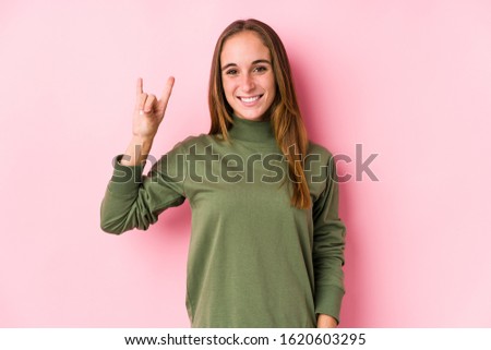 Young caucasian woman posing isolated  showing a horns gesture as a revolution concept.