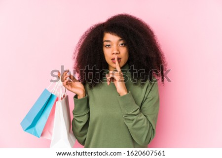 Young afro woman shopping isolated Young afro woman buying isolaYoung afro woman holding a roses isolated keeping a secret or asking for silence.< mixto >