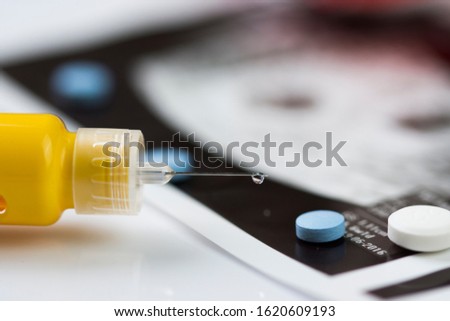 Ultrasonogram picture, syringe with a thin needle and some pills.