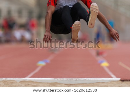 Athlete in long jump during competition, performing triple long jump on races Royalty-Free Stock Photo #1620612538