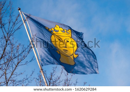 Stockholm city flag with a yellow female face in a crown on a blue background
