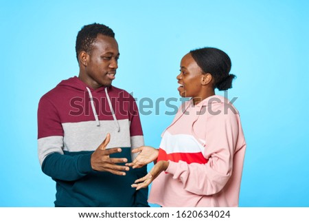 An African man and a woman in warm jackets are gesturing with their hands