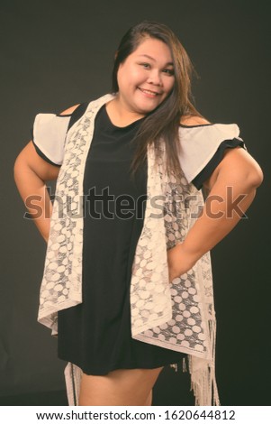 Beautiful overweight Asian woman against black background