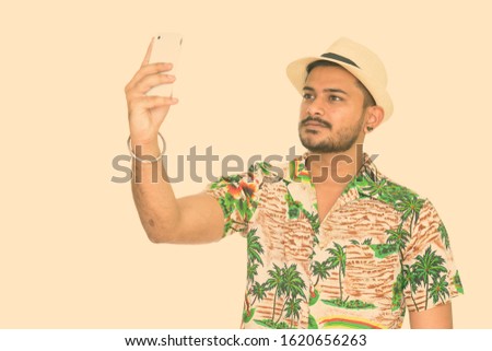 Young handsome Indian man ready for vacation taking selfie