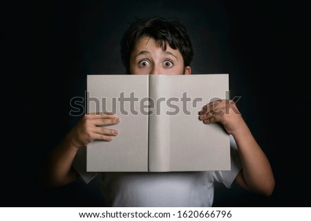 curious child with book on black background