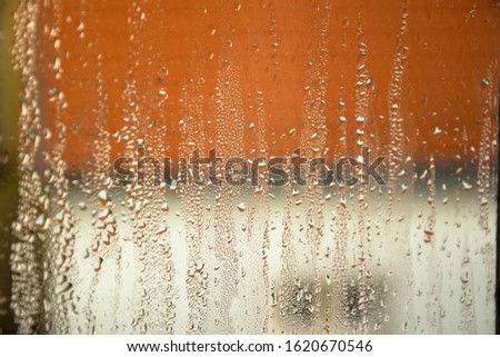 Raindrops on the window autumn mood red roof in the background