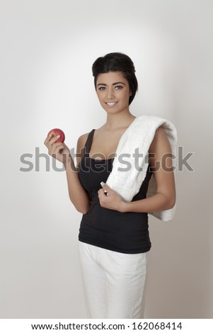 young asian woman in fitness equipment with towel  holding an apple