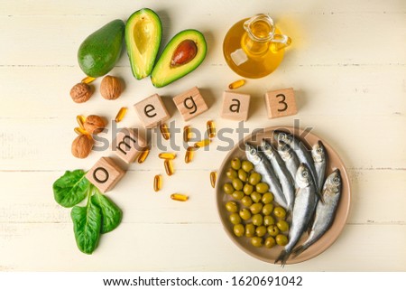Wooden cubes, healthy products with high omega 3 and fish oil pills on white table Royalty-Free Stock Photo #1620691042